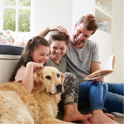 Two Children Reading With Dad And Dog While Smiling